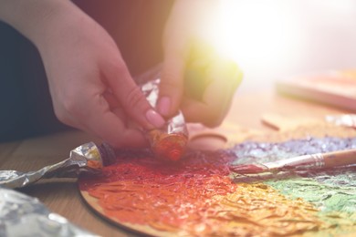 Image of Artist squeezing paint onto palette in sunlit studio, closeup