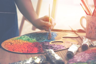 Image of Artist mixing paints with brush on palette, closeup