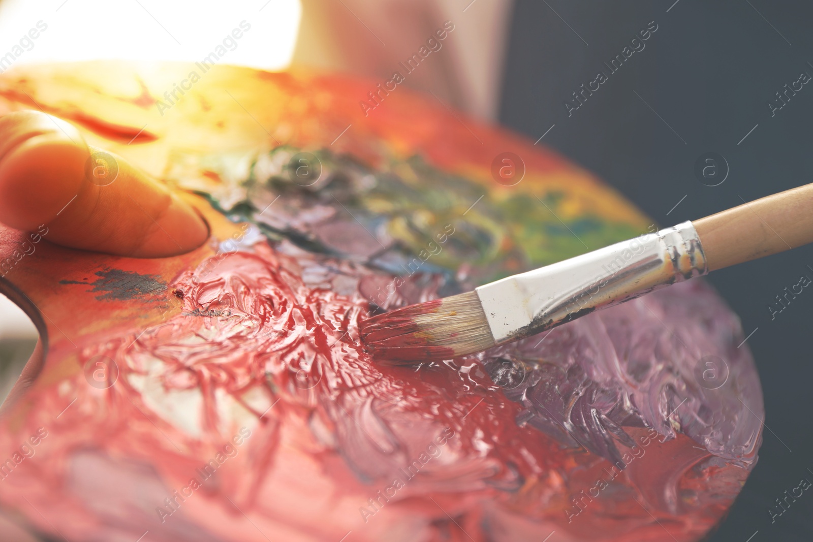 Image of Artist mixing paints with brush on palette, closeup