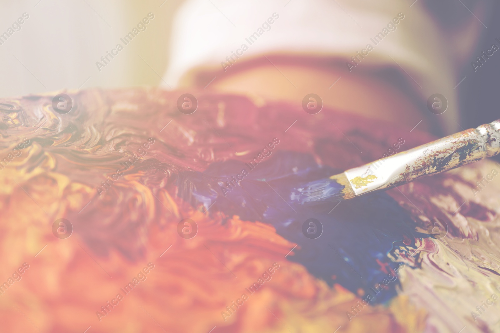 Image of Artist mixing paints with brush on palette, closeup