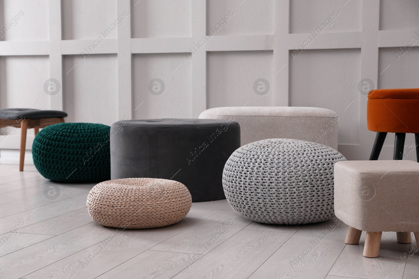 Photo of Different stylish poufs and ottomans near white wall