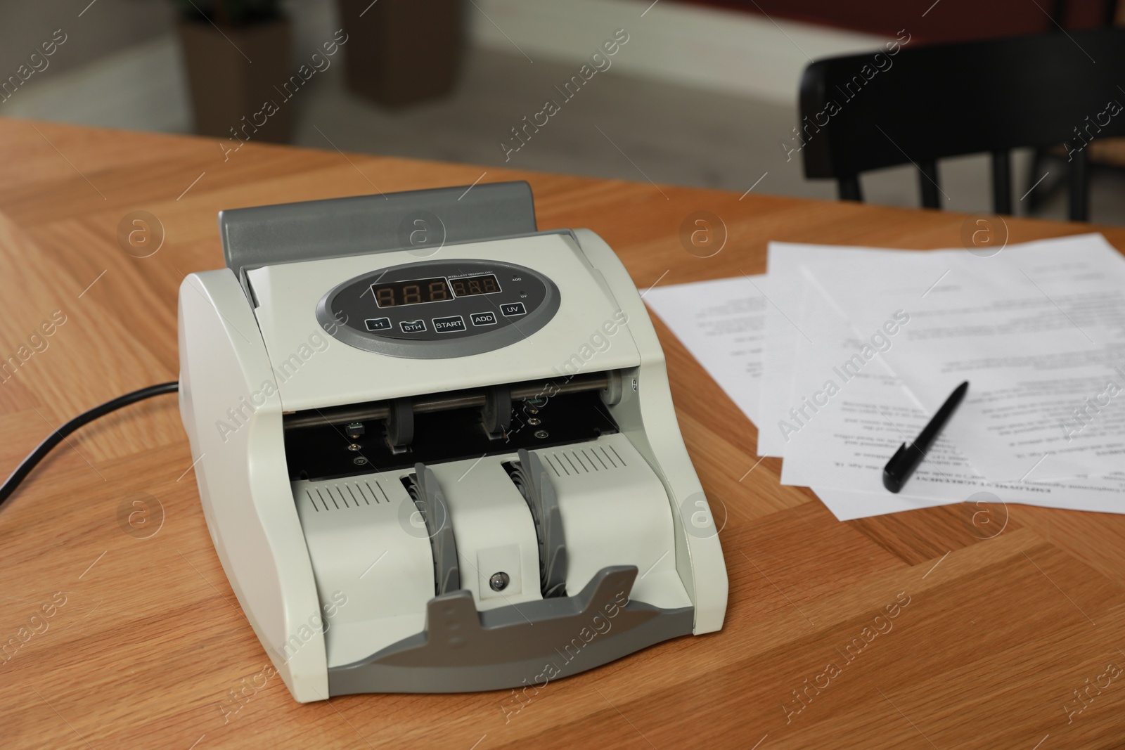 Photo of Modern banknote counter on wooden table indoors