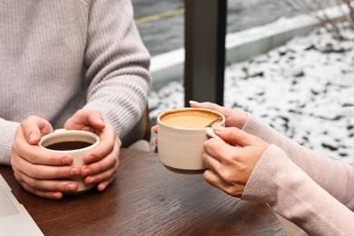 Photo of Colleagues having coffee break at wooden table in cafe, closeup