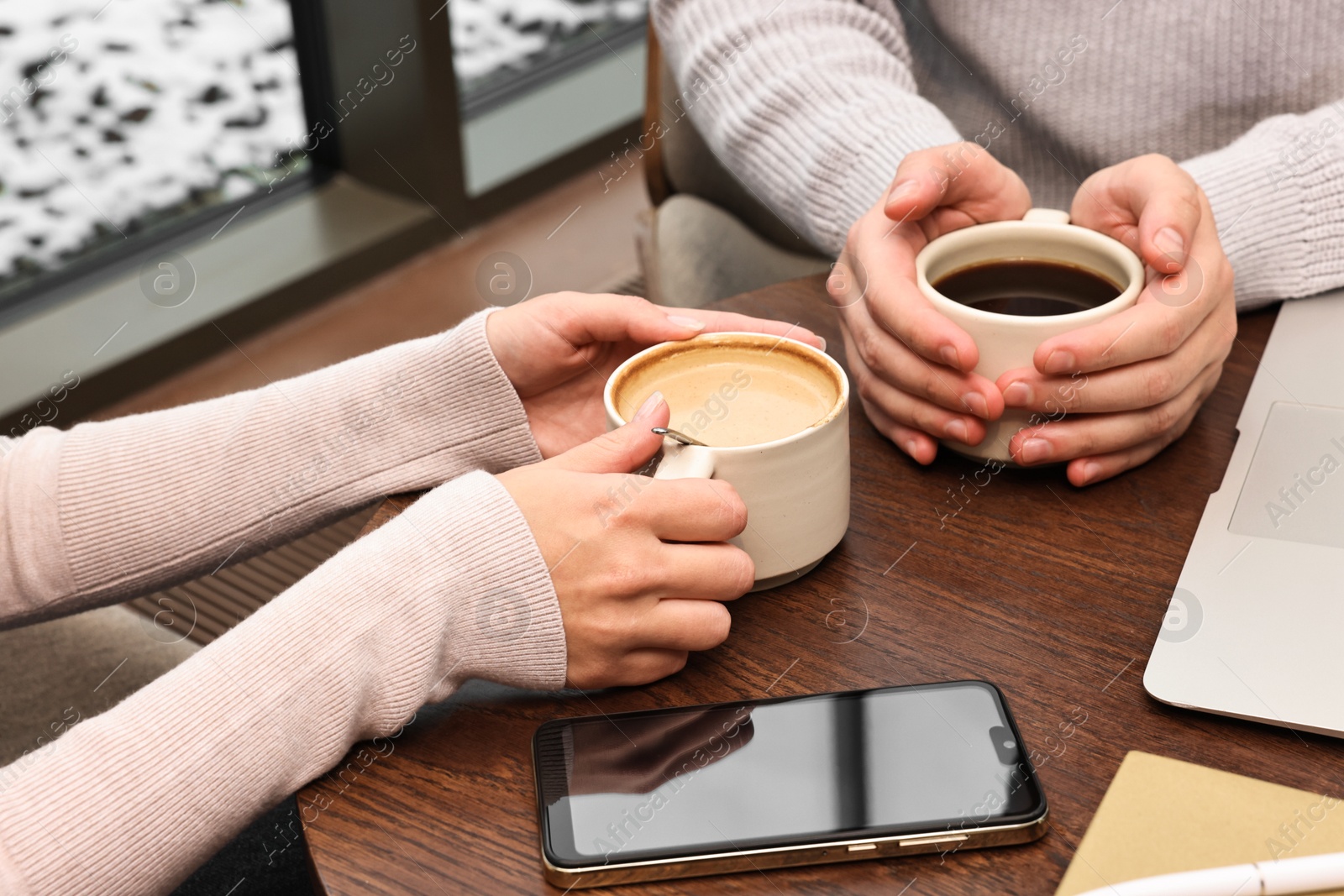 Photo of Colleagues having coffee break at wooden table in cafe, closeup