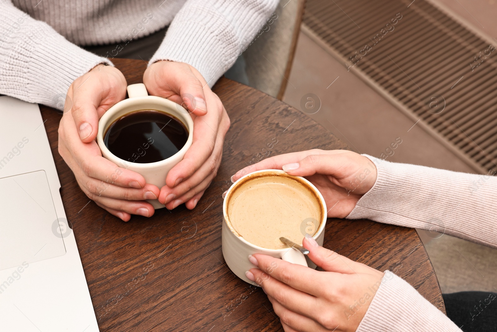 Photo of Colleagues having coffee break at wooden table in cafe, closeup