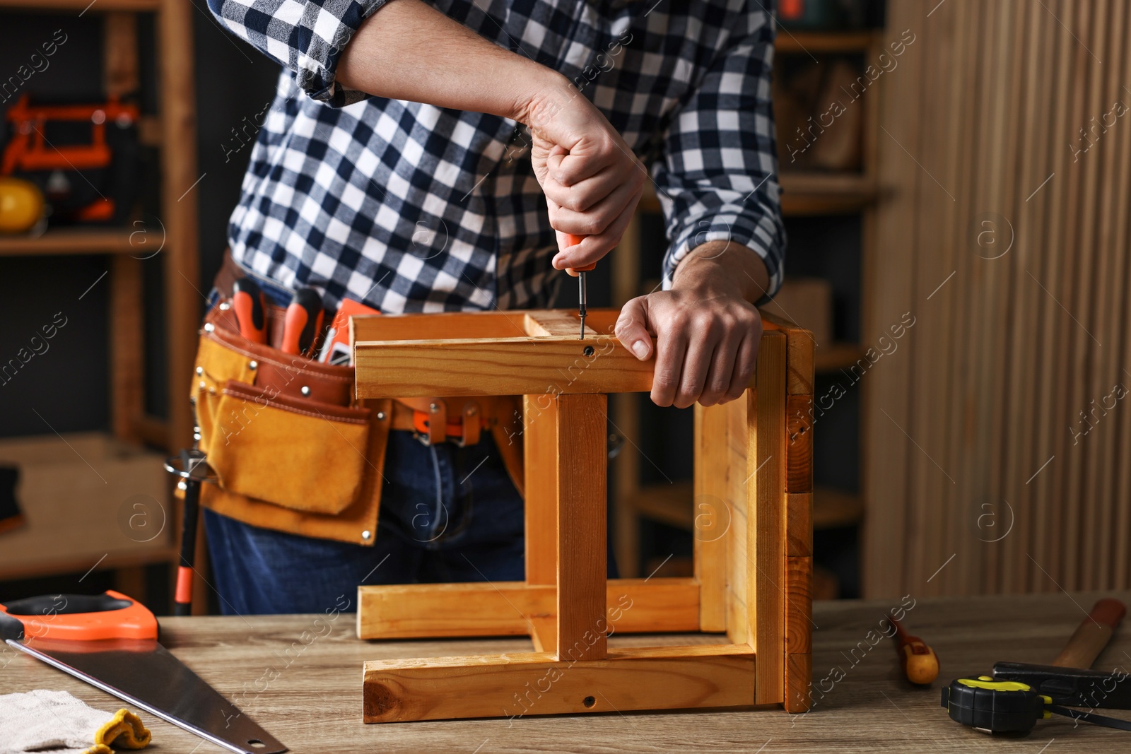 Photo of Carpenter repairing stool at table in workshop, closeup