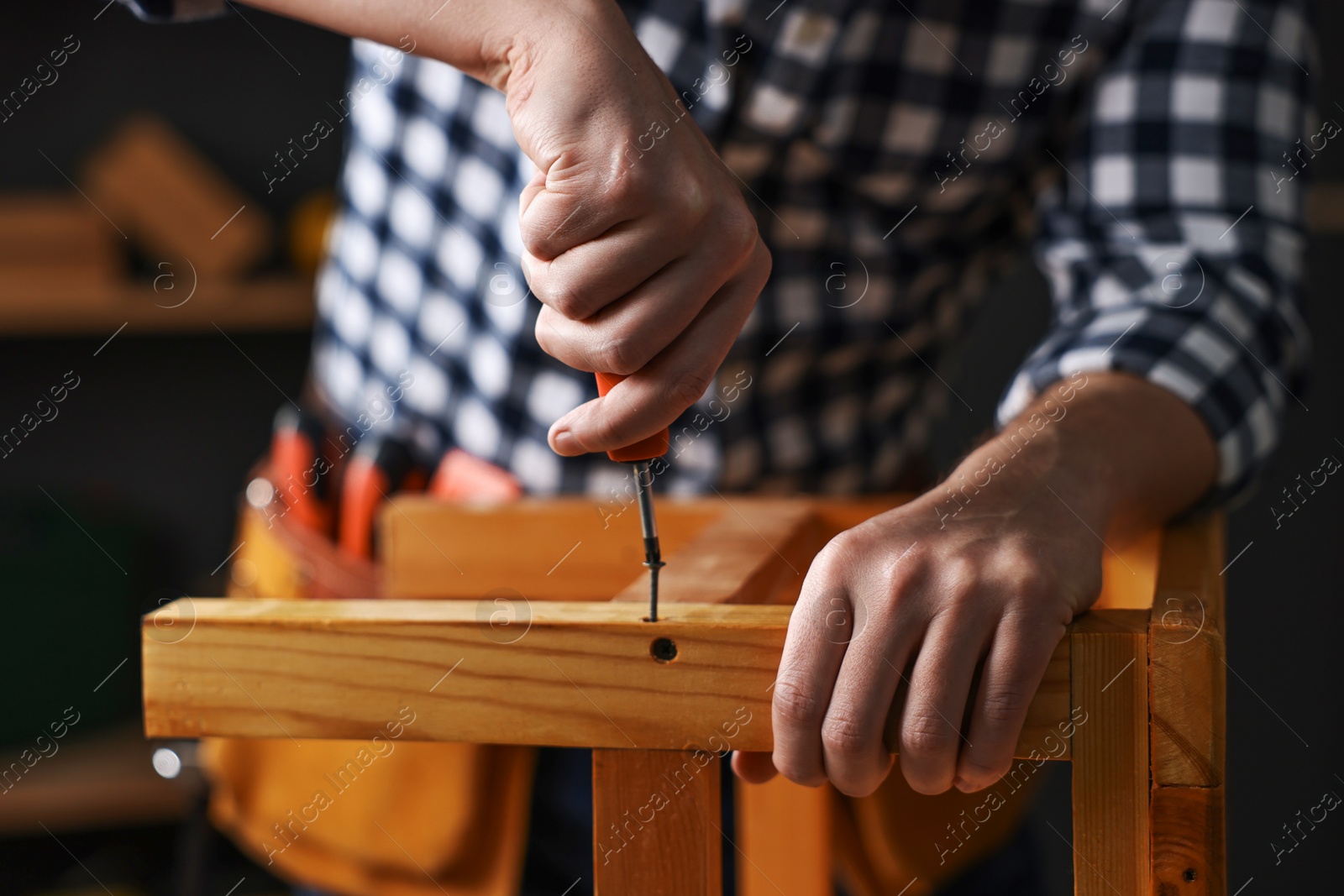 Photo of Carpenter repairing wooden stool in workshop, closeup