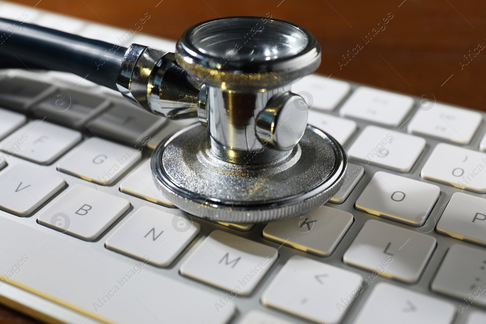 Photo of Technical support concept. Stethoscope and keyboard on wooden table, closeup