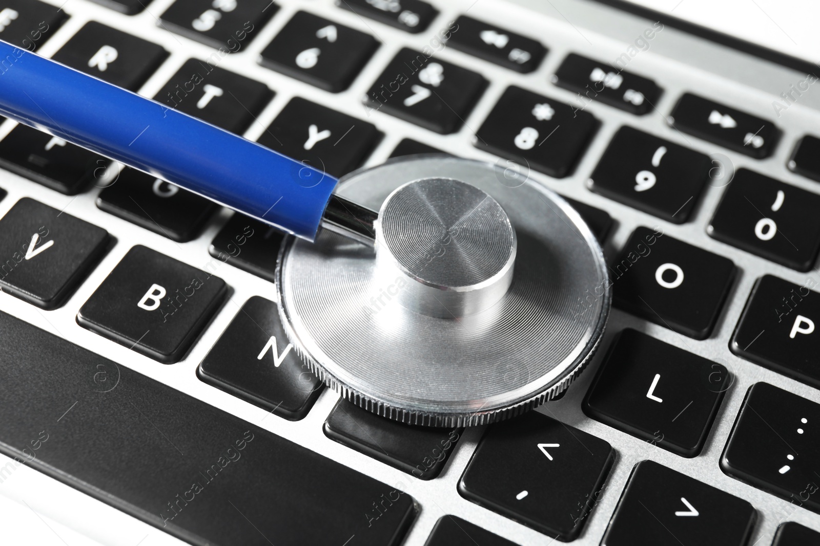 Photo of Technical support concept. Stethoscope on laptop keyboard, closeup