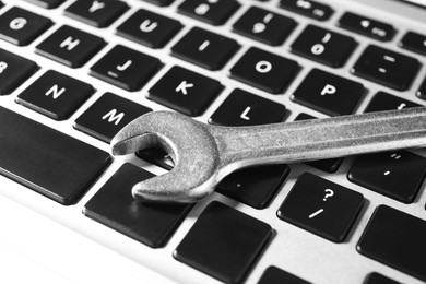 Photo of Technical support concept. Wrench on laptop keyboard, closeup