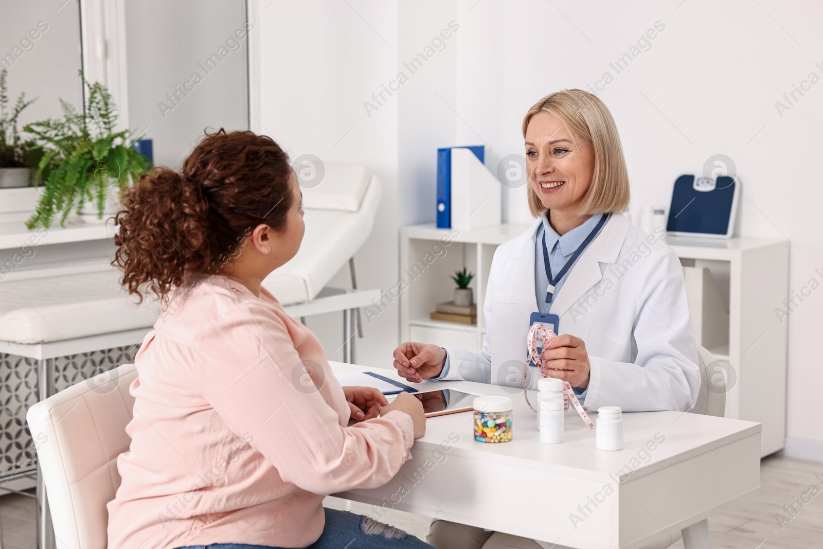 Photo of Weight loss. Smiling nutritionist consulting patient at table in clinic