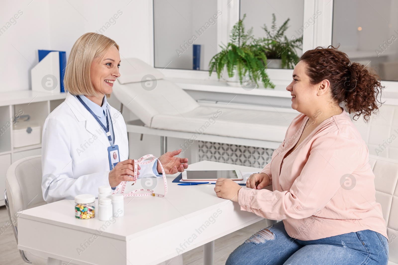 Photo of Weight loss. Smiling nutritionist consulting patient at table in clinic