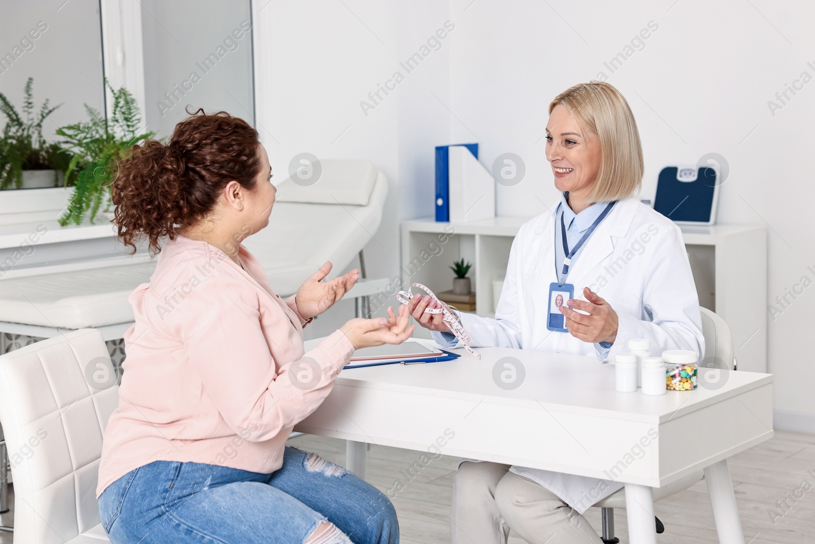 Photo of Weight loss. Smiling nutritionist consulting patient at table in clinic