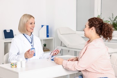 Photo of Weight loss. Smiling nutritionist consulting patient at table in clinic