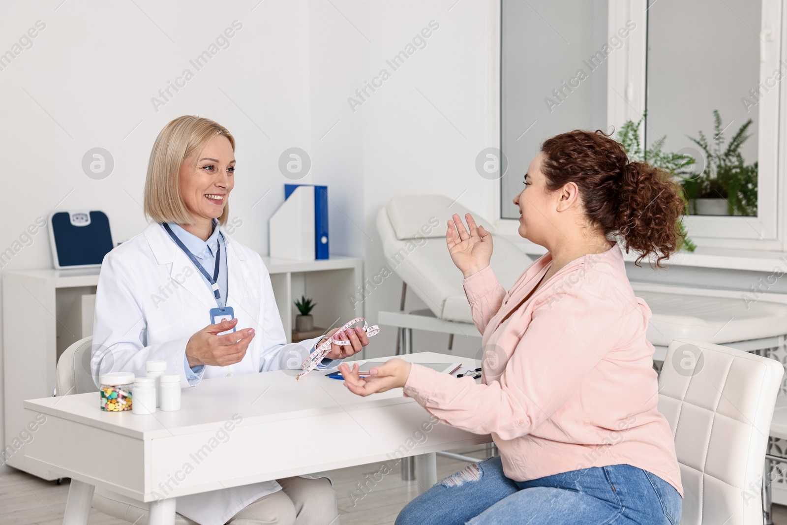 Photo of Weight loss. Smiling nutritionist consulting patient at table in clinic