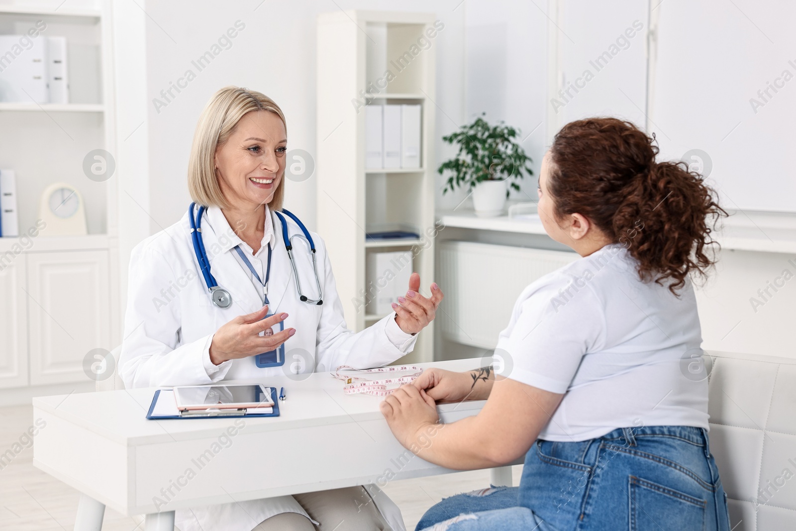 Photo of Weight loss. Smiling nutritionist consulting patient at table in clinic