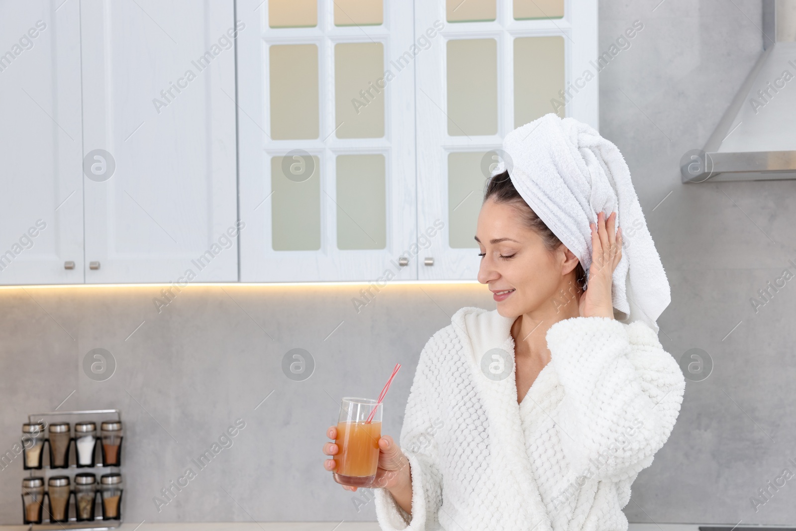 Photo of Beautiful woman with glass of juice after spa procedure in kitchen