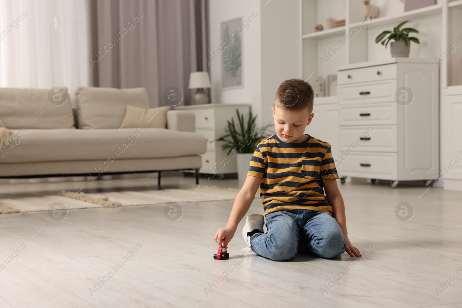 Photo of Little boy playing with toy car at home. Space for text