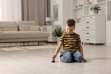 Photo of Little boy playing with toy car at home. Space for text