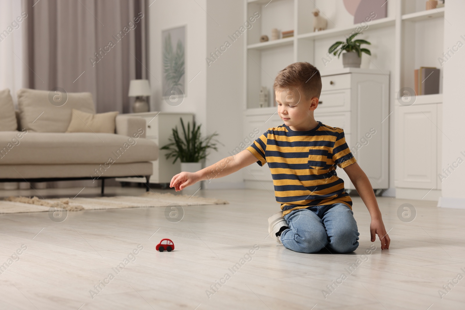 Photo of Little boy playing with toy car at home. Space for text