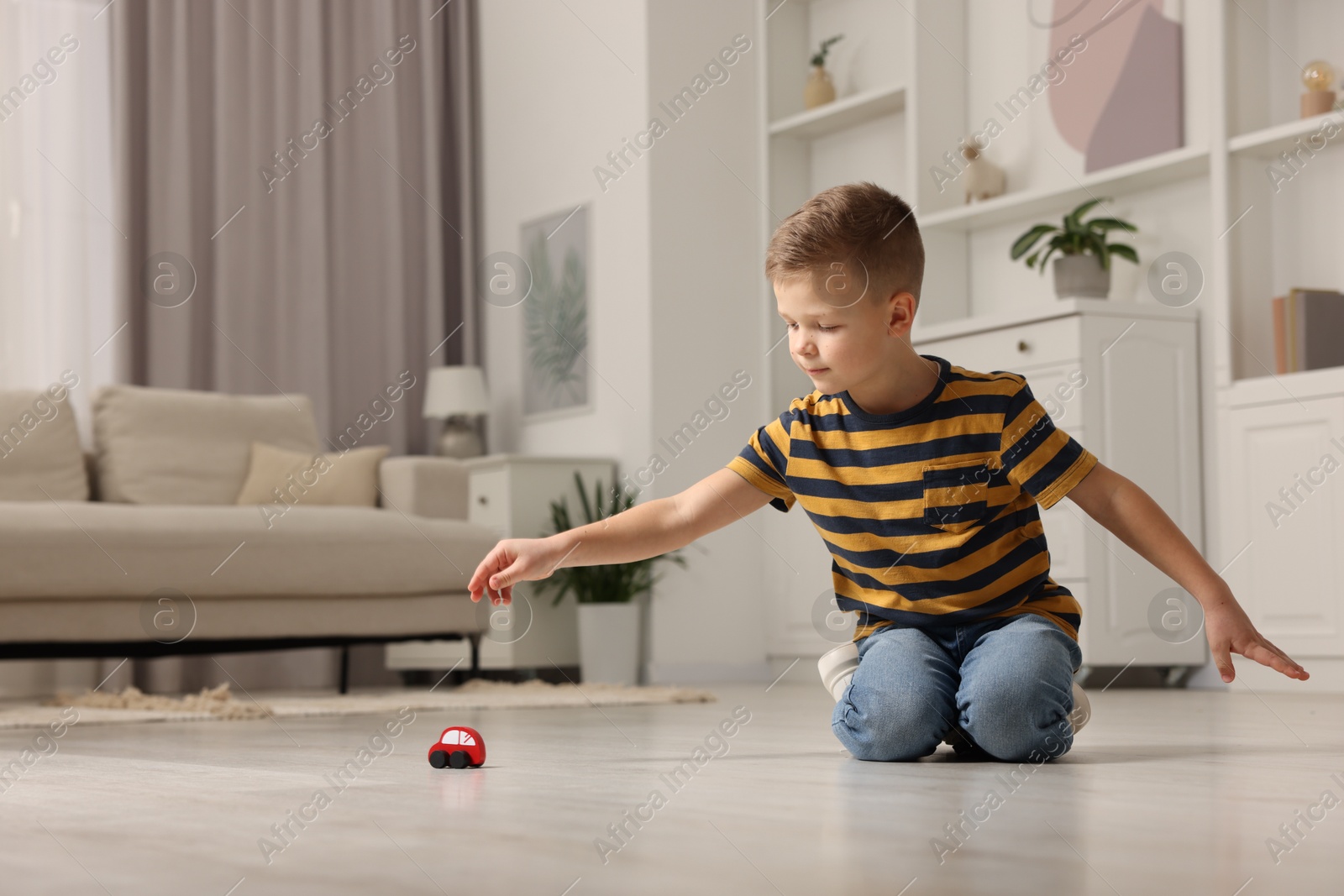 Photo of Little boy playing with toy car at home. Space for text