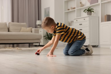 Photo of Little boy playing with toy car at home