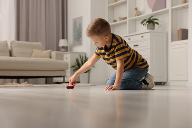 Photo of Little boy playing with toy car at home