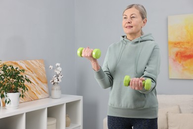 Photo of Elderly woman exercising with dumbbells at home