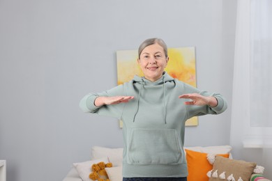 Photo of Smiling elderly woman doing exercise at home. Space for text