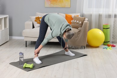 Photo of Elderly woman doing exercise at home. Healthy leisure