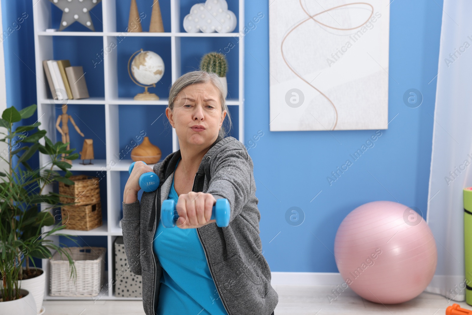 Photo of Elderly woman exercising with dumbbells at home