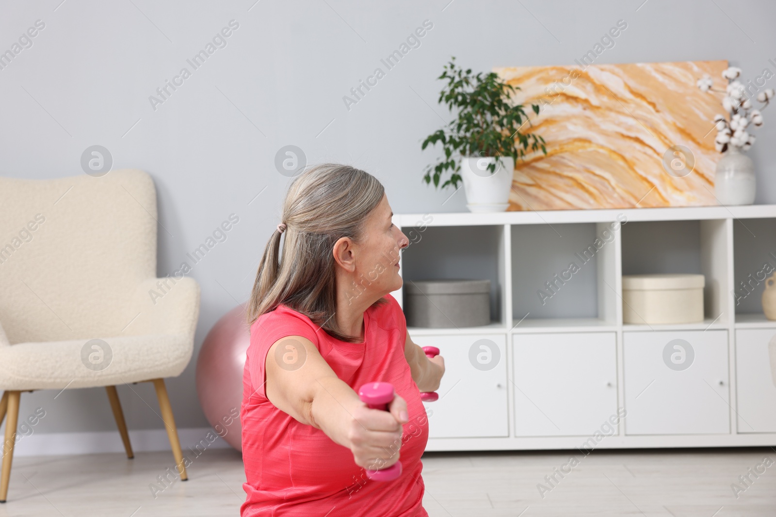 Photo of Elderly woman exercising with dumbbells at home