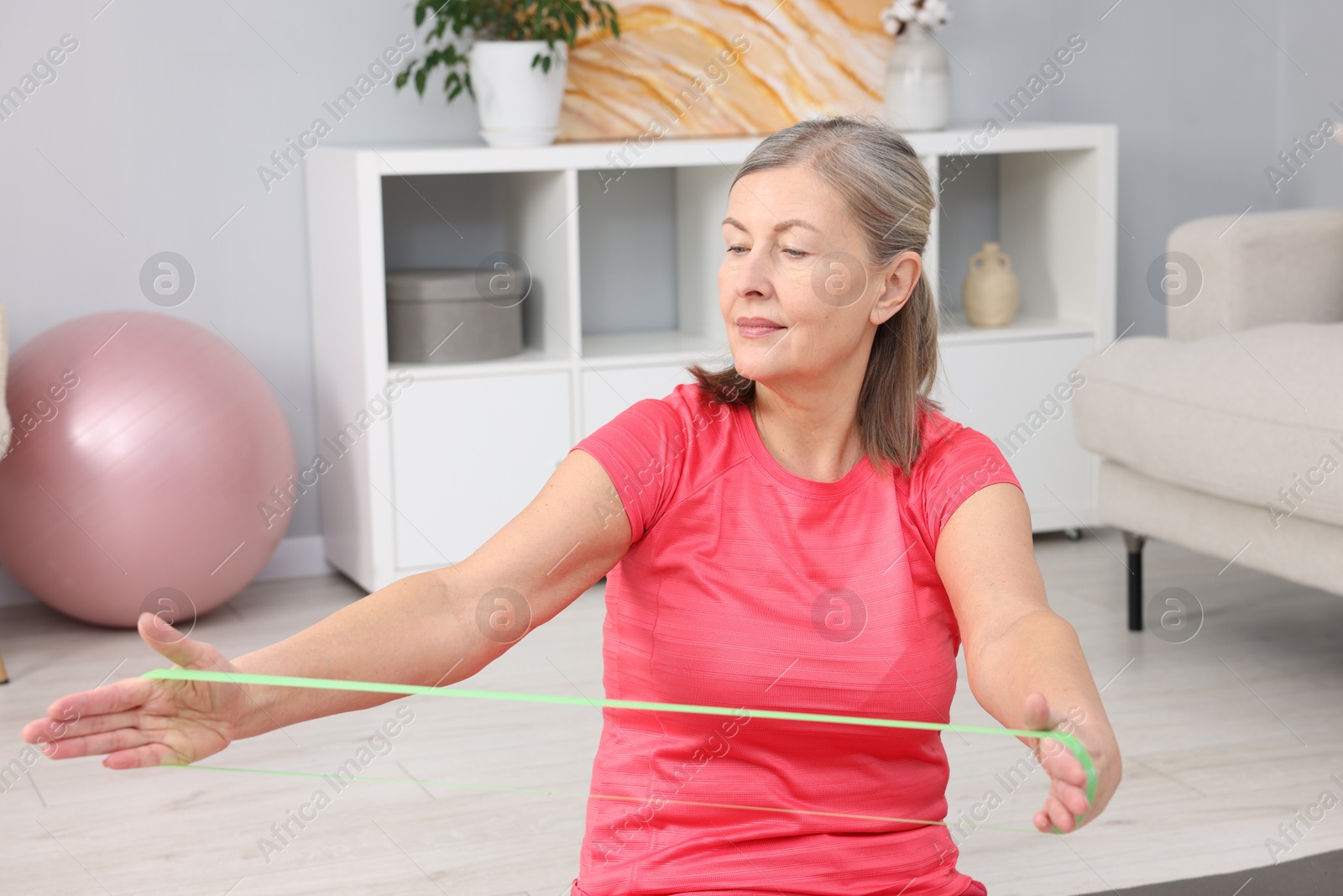 Photo of Elderly woman exercising with fitness elastic band at home