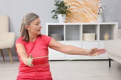 Photo of Elderly woman exercising with fitness elastic band at home