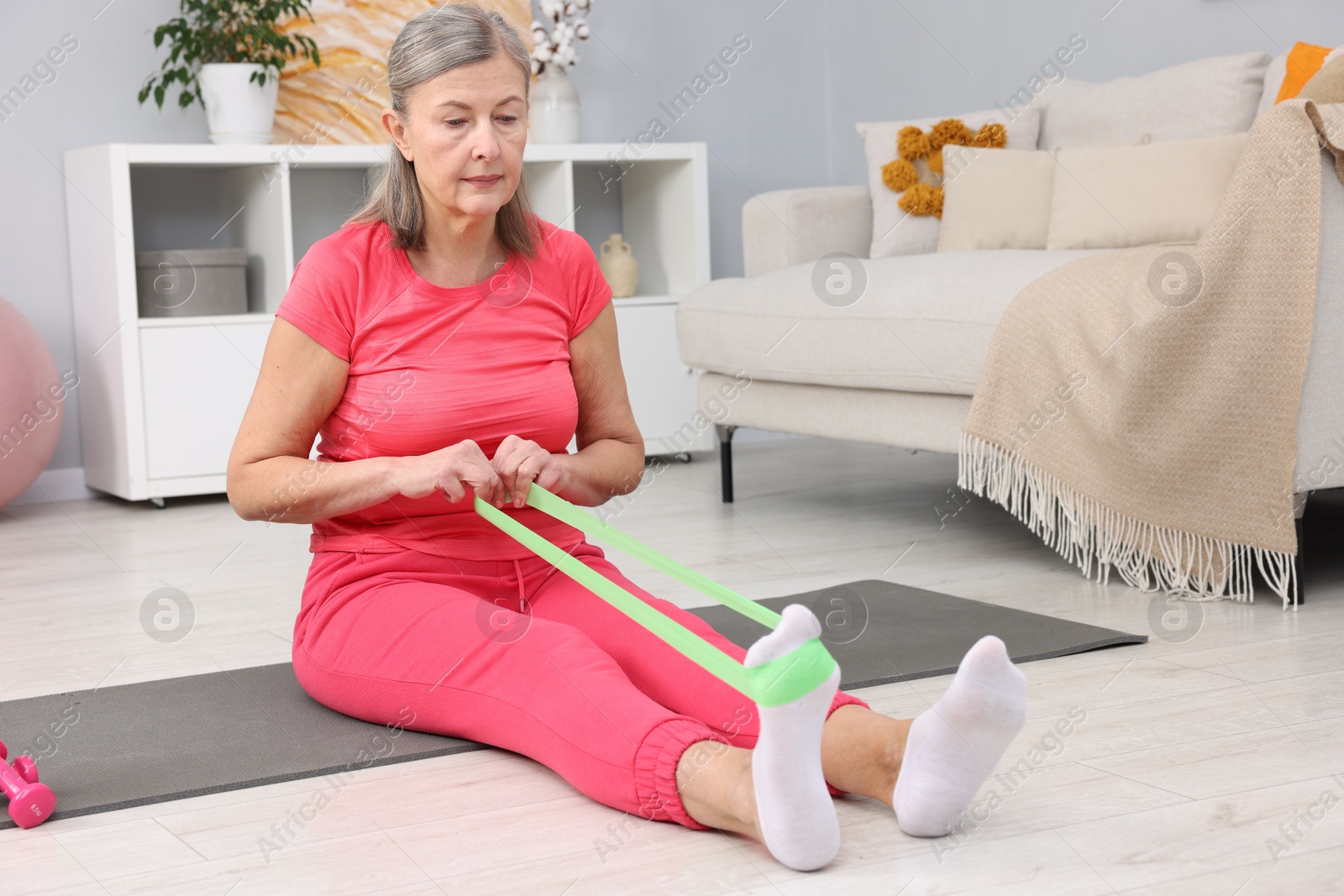 Photo of Elderly woman exercising with fitness elastic band at home