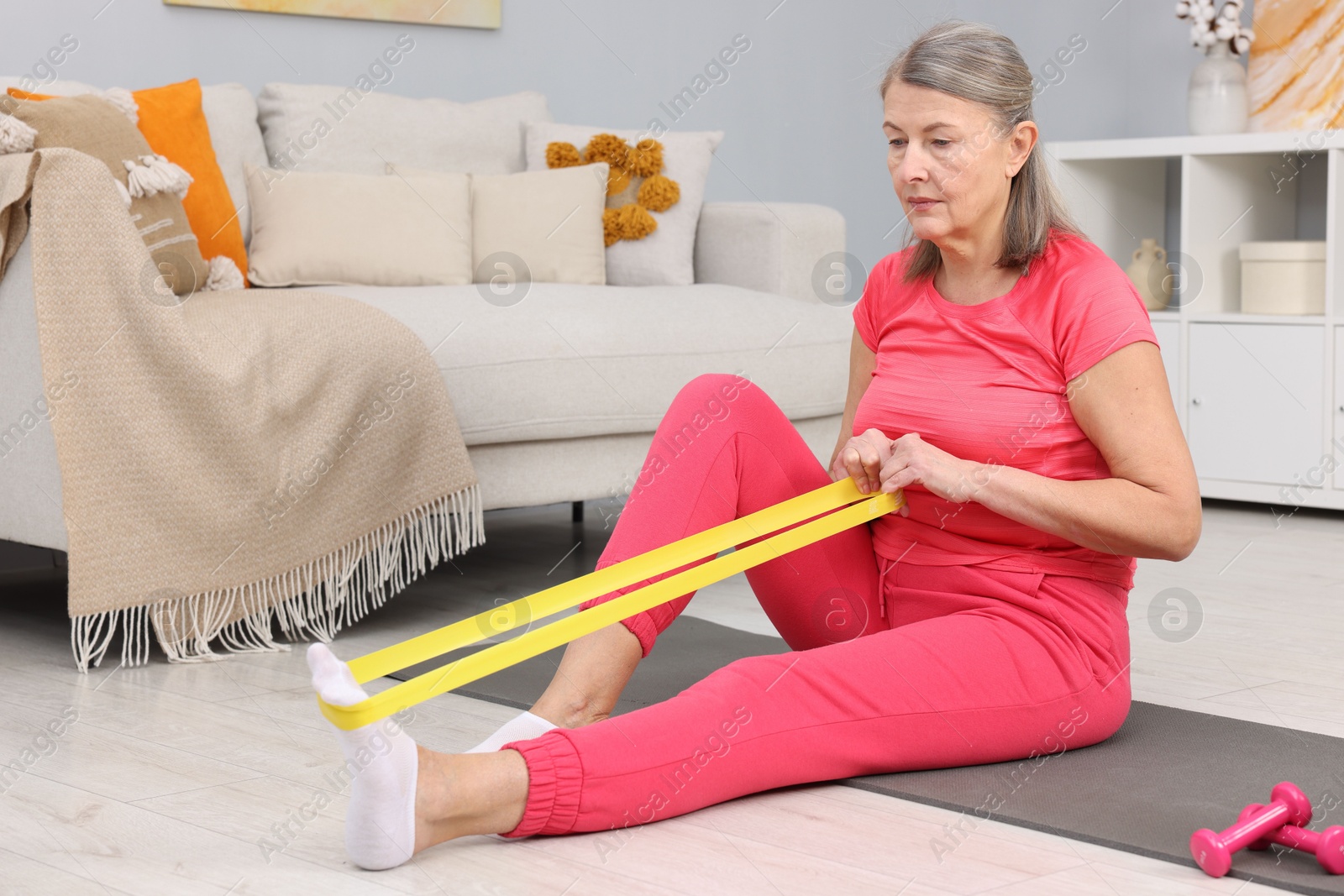 Photo of Elderly woman exercising with fitness elastic band at home