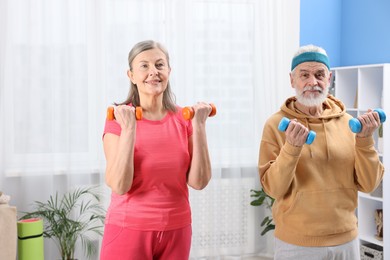 Photo of Elderly couple exercising with dumbbells at home