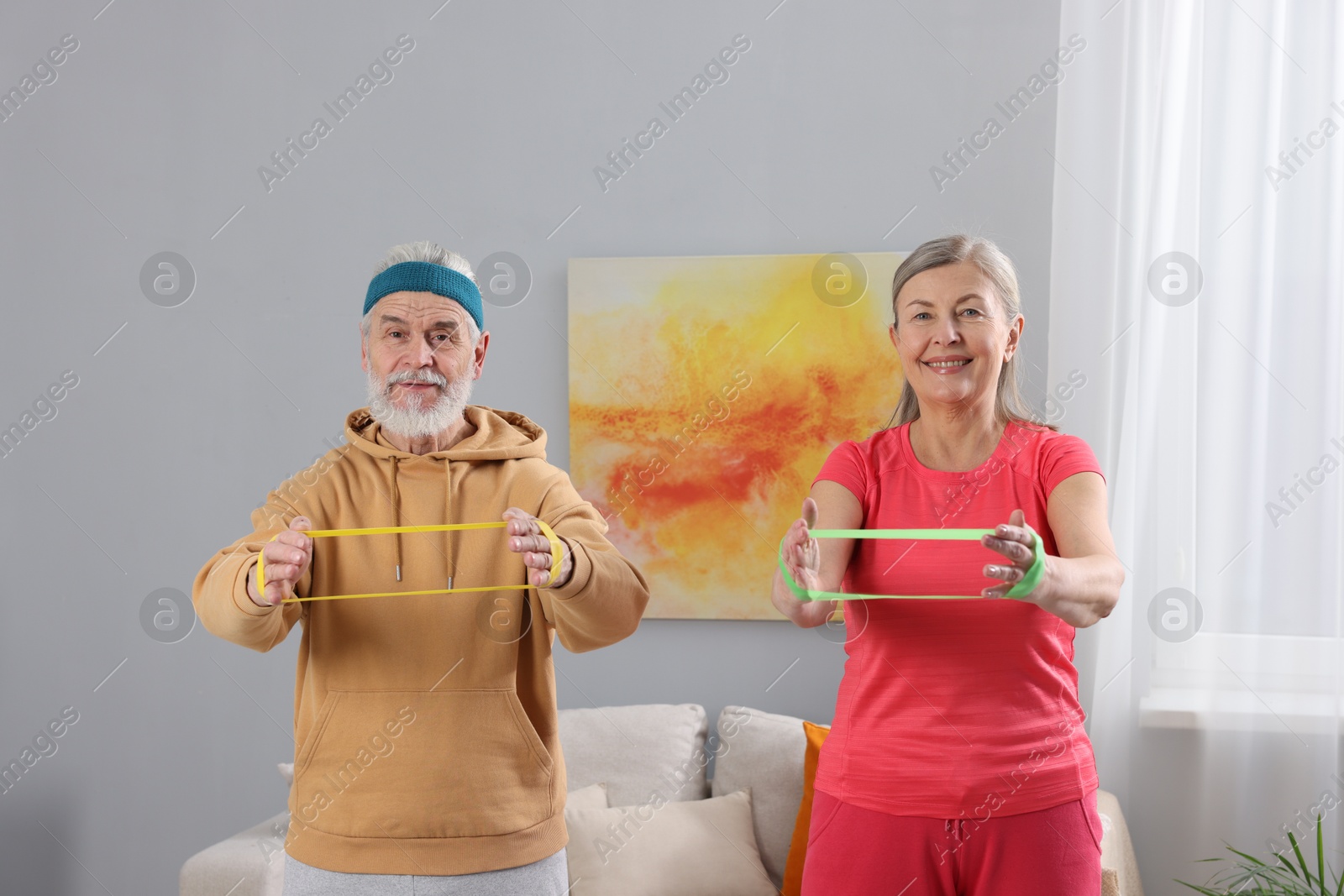 Photo of Elderly couple exercising with fitness elastic bands at home