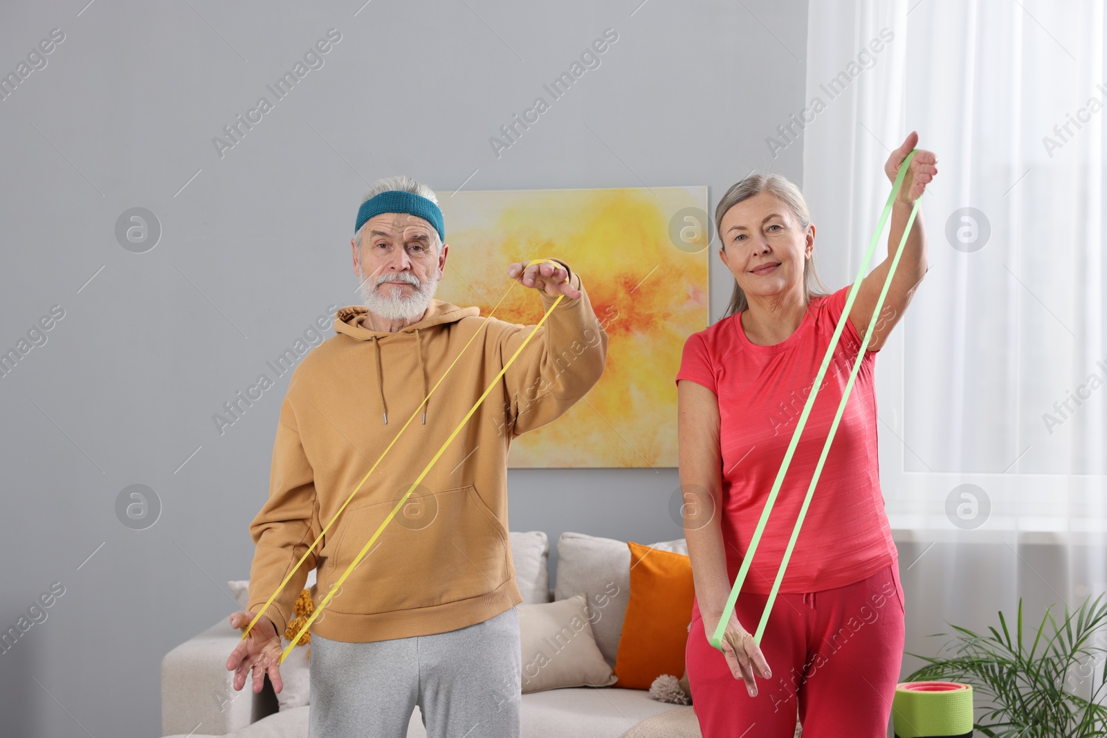 Photo of Elderly couple exercising with fitness elastic bands at home