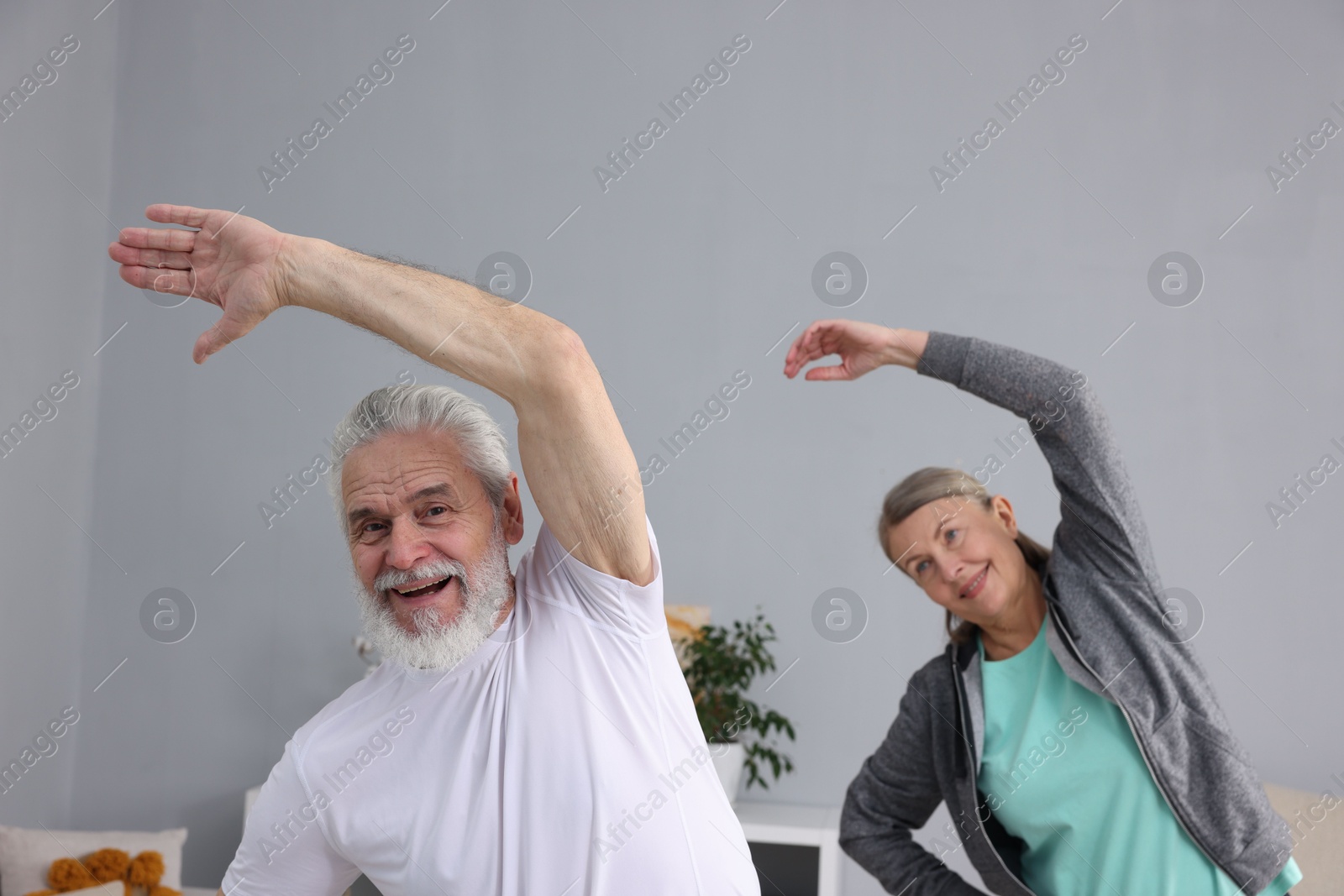 Photo of Smiling elderly couple exercising at home. Healthy leisure