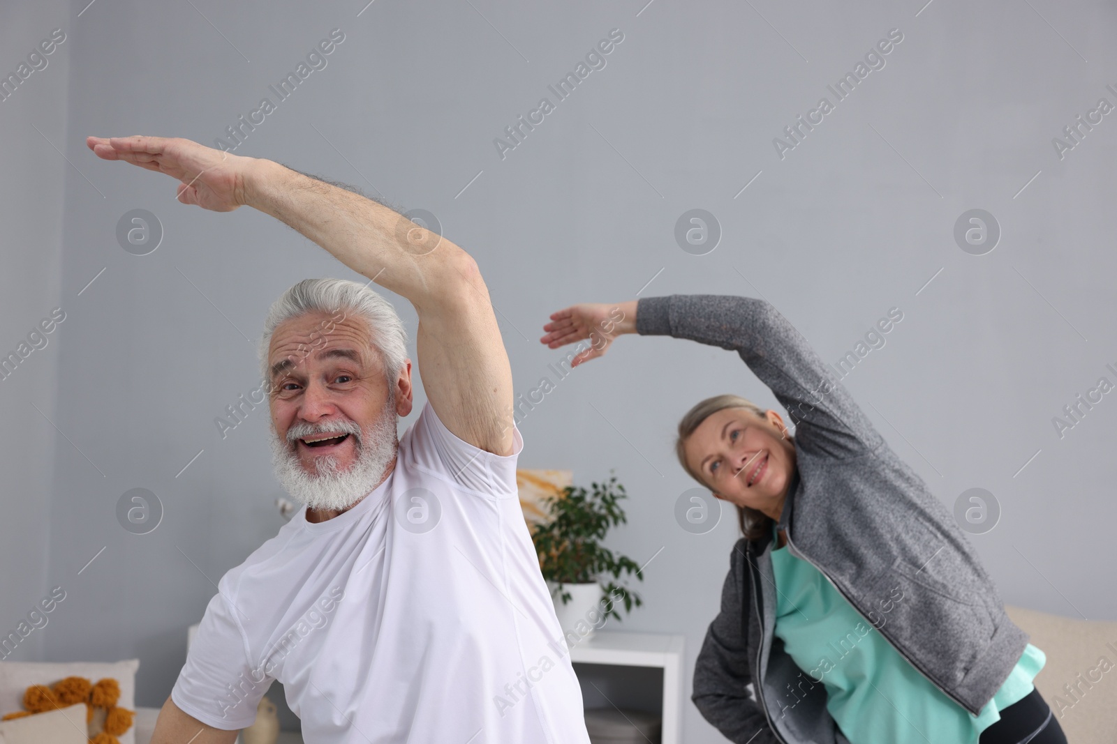 Photo of Smiling elderly couple exercising at home. Healthy leisure