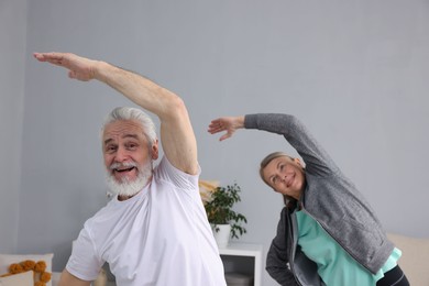 Smiling elderly couple exercising at home. Healthy leisure