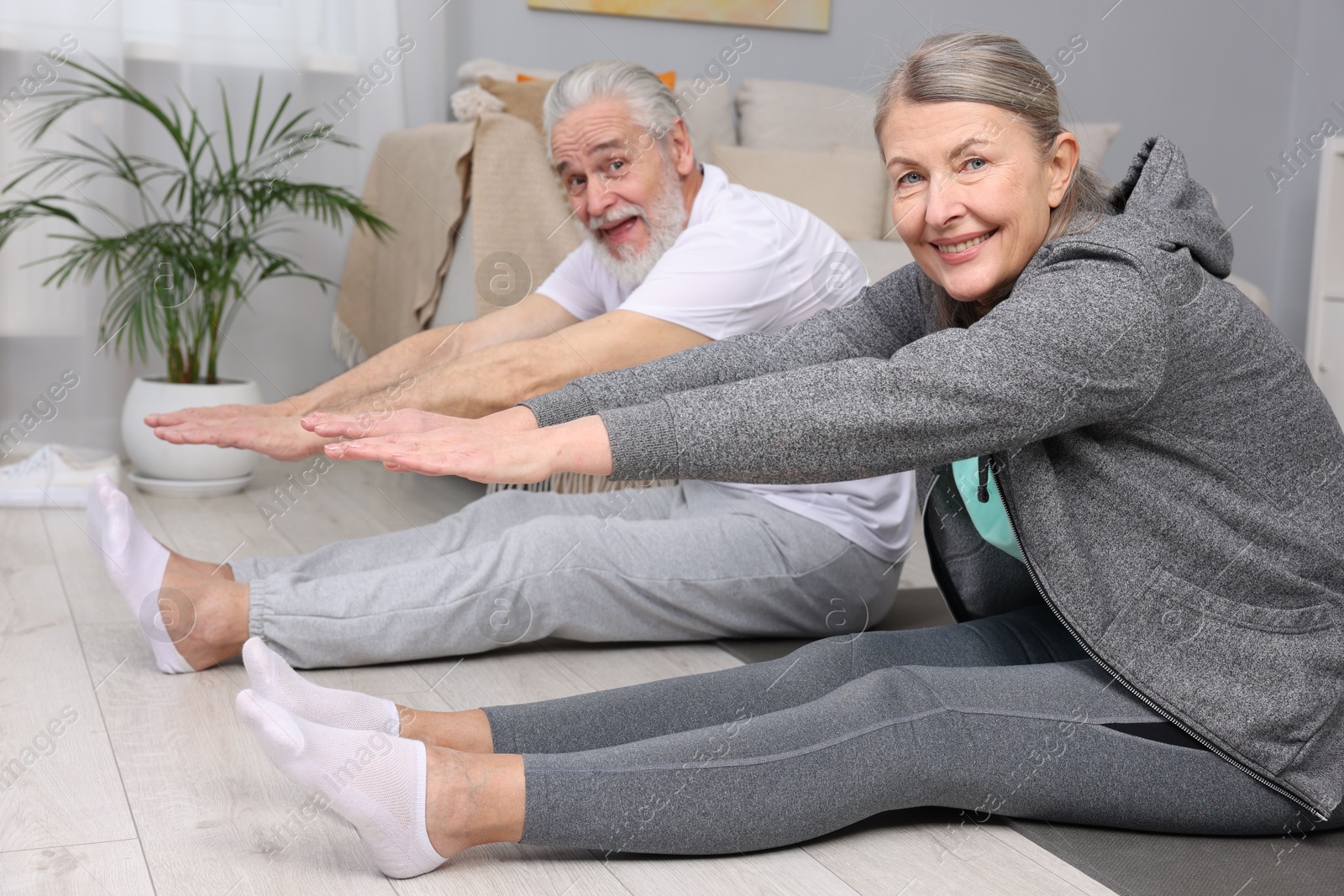 Photo of Smiling elderly couple exercising at home. Healthy leisure