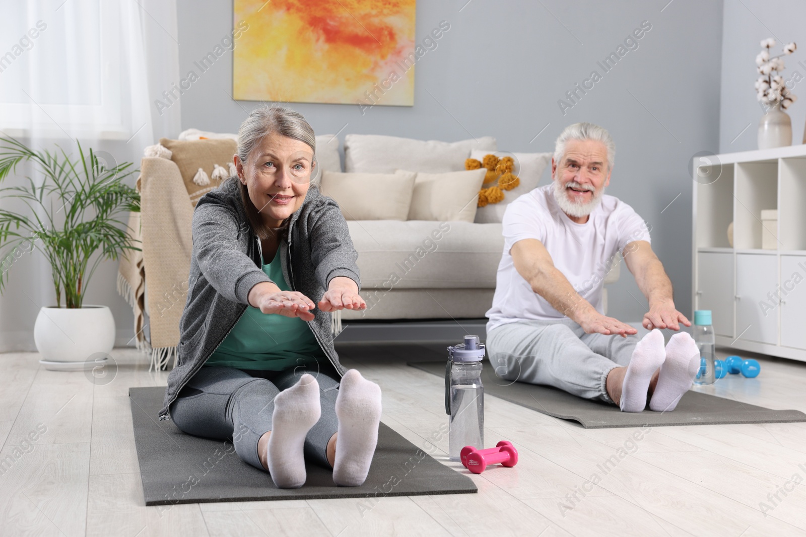 Photo of Smiling elderly couple exercising at home. Healthy leisure