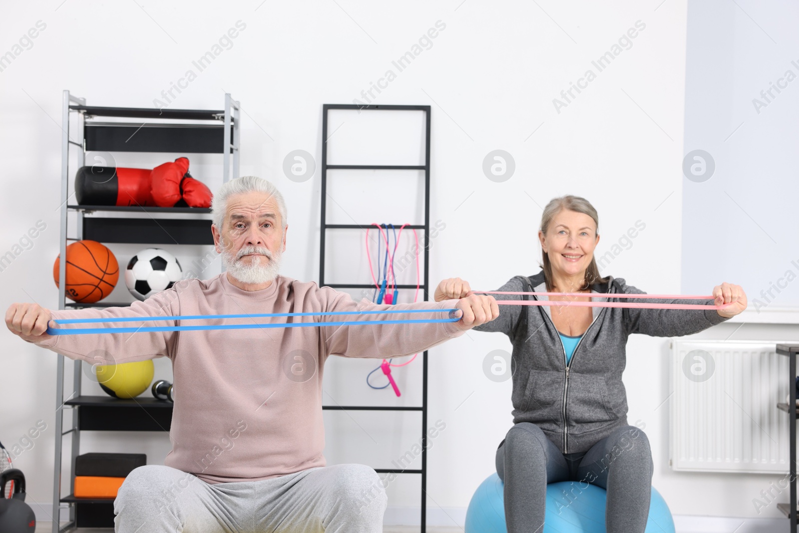 Photo of Elderly couple exercising with elastic bands and fitness balls at home