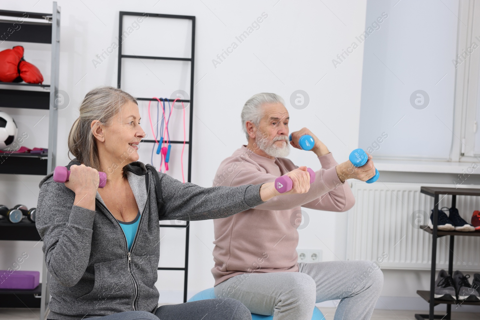 Photo of Elderly couple exercising with dumbbells at home