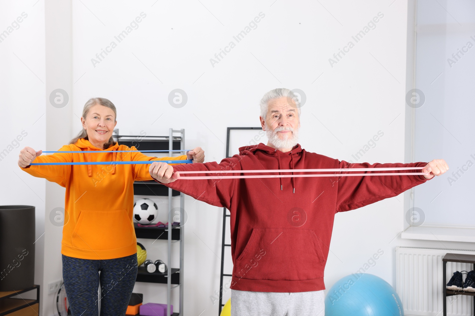 Photo of Elderly couple exercising with fitness elastic bands at home