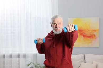 Photo of Elderly man exercising with dumbbells at home