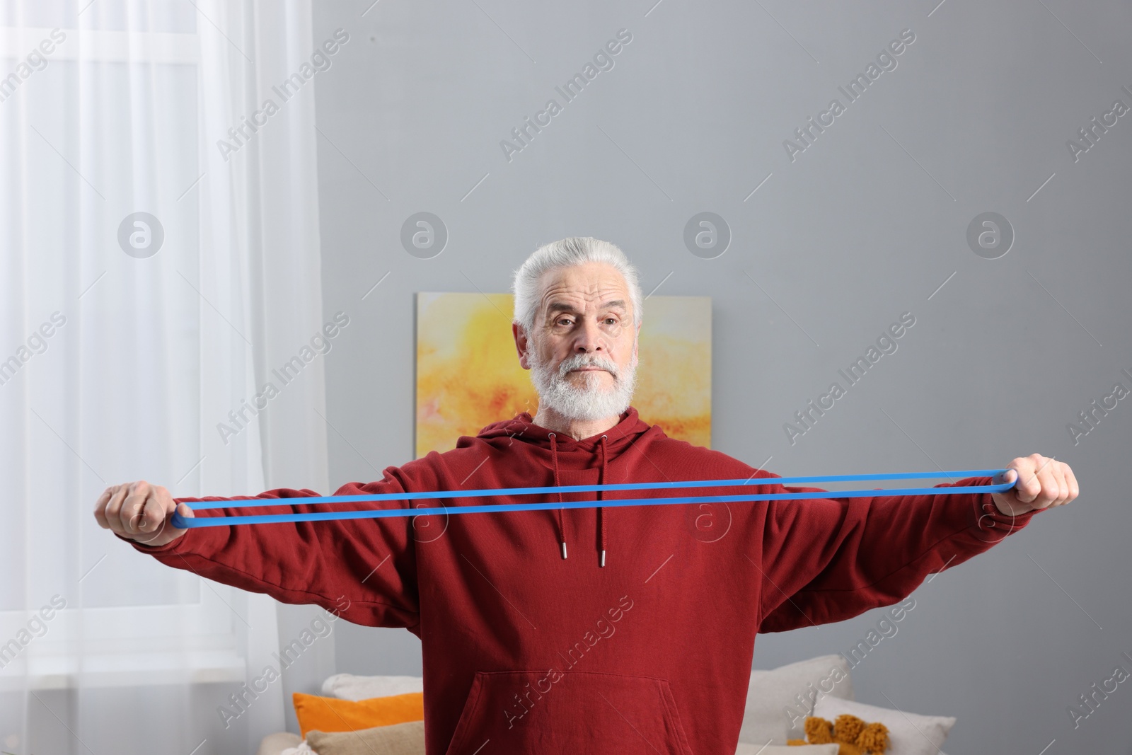 Photo of Elderly man exercising with dumbbells at home