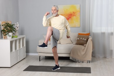 Photo of Elderly man exercising at home. Healthy leisure